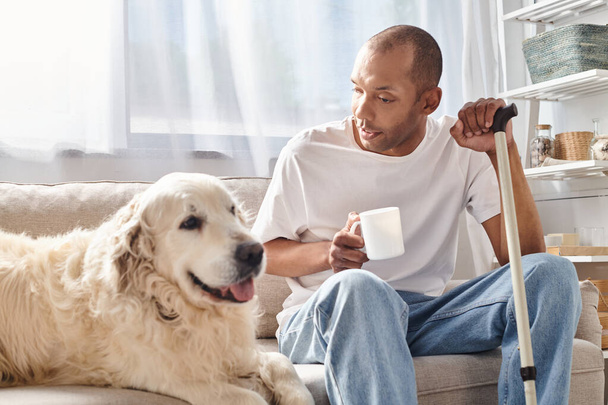 A man with myasthenia gravis sits on a couch, enjoying company with his loyal Labrador dog in a cozy living room setting. - 写真・画像
