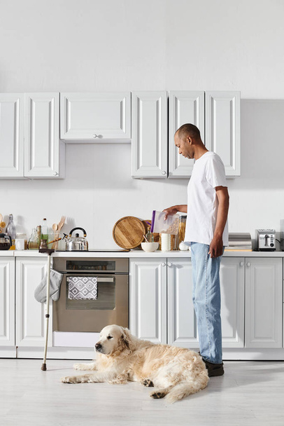 An African American man with myasthenia gravis stands alongside his loyal Labrador dog in a cozy kitchen setting. - Фото, изображение