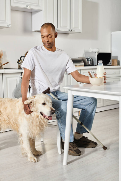 Egy rokkant afro-amerikai férfi osztozik egy csendes pillanaton a konyhaasztalnál a hűséges labrador kutyájával.. - Fotó, kép