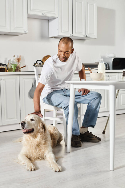 Un uomo afroamericano disabile siede a un tavolo con il suo cane Labrador, entrambi godendo di un momento di pace insieme. - Foto, immagini
