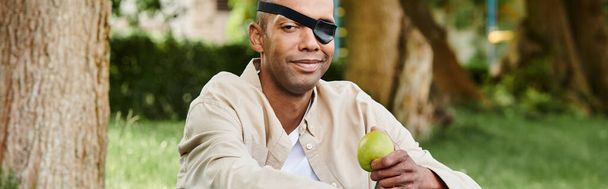 Un afroamericano con los ojos vendados sostiene una manzana, simbolizando la diversidad y la inclusión en la sociedad. - Foto, imagen