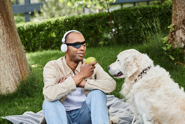Egy myasthenia gravis-os férfi ül egy takarón egy fehér labrador kutya mellett a sokszínűség és befogadás nyugodt pillanatában.. - Fotó, kép