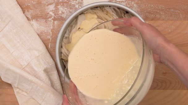 クリームチーズのレシピでいっぱいのフィロ生地ペストリー. 女性の手は生地の層,クローズアップ ベーキング プロセス,平らな層,木の背景を転がしました - 映像、動画