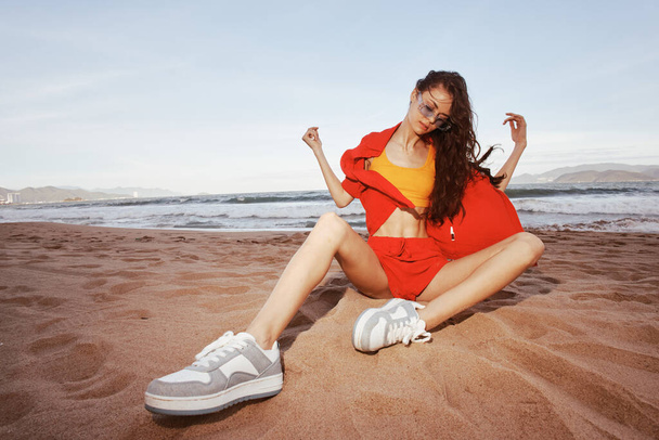 Glimlachende vrouw op het strand, op vakantie met trendy modekleding: "Zorgeloze schoonheid omarmt natuur geluk aan zee - Foto, afbeelding