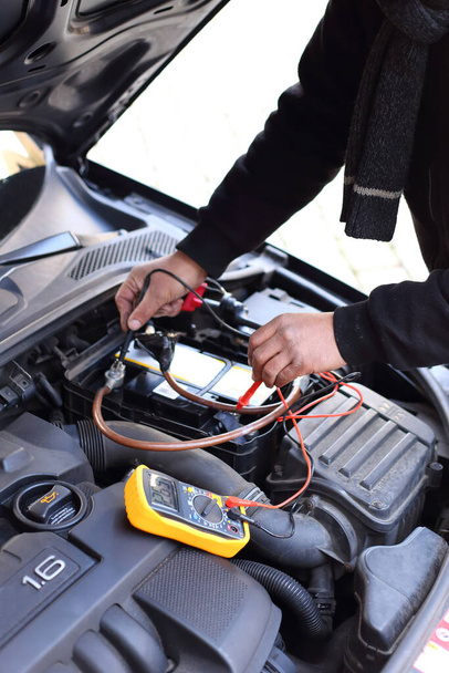 Un mecánico de automóvil inspeccionando un automóvil usando un dispositivo de diagnóstico electrónico - Foto, Imagen