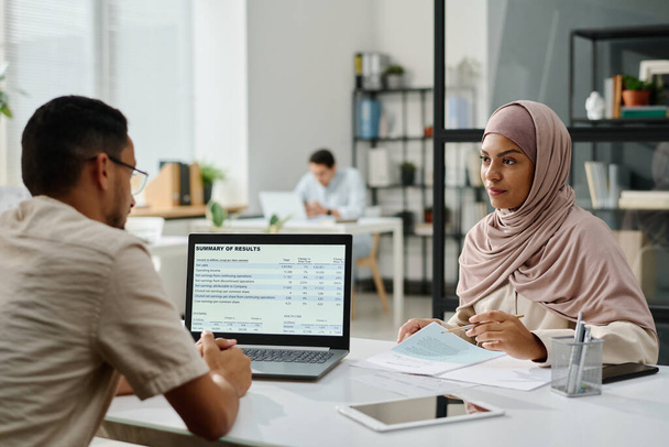 Двоє молодих міжкультурних мусульманських бізнесменів дивляться один на одного на зустрічі за робочим місцем під час обговорення робочих місць - Фото, зображення