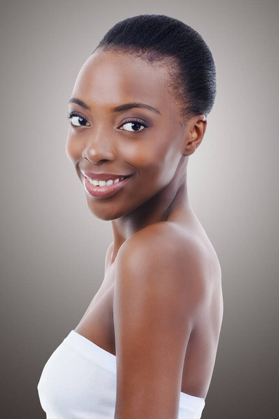 Soins de la peau, dermatologie et portrait de femme noire en studio avec sourire, maquillage naturel ou éclat du visage. Cosmétiques, beauté et visage de fille heureuse sur fond gris pour une peau, une brillance ou un bien-être sains - Photo, image