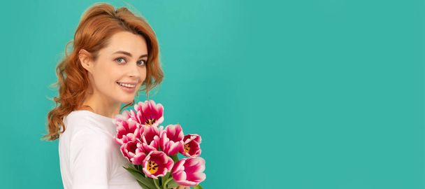 Girl with spring tulips flowers. happy girl portrait with tulip flower bouquet on blue background. Woman isolated face portrait, banner with mock up copyspace - Foto, afbeelding