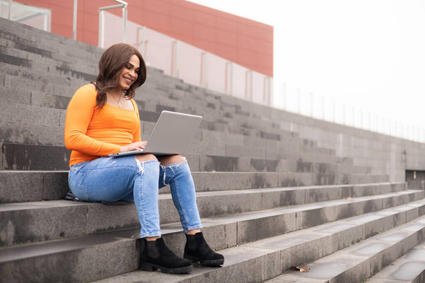 Estudiante trans de género trabajando en laptop en campus al aire libre. Foto de alta calidad - Foto, imagen