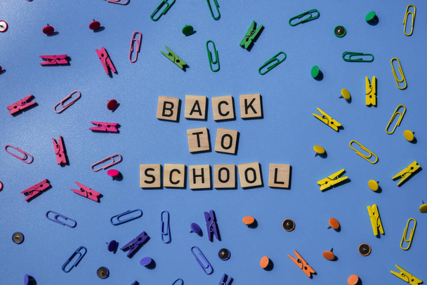 VISSZA SCHOOL üzenetet felirat szöveg fa blokkok kreatív színes kék háttér írószer kellékek körül. Oktatási köszöntő hirdetmény diákoknak és tanároknak. Top view flat lay Az új tanév koncepciója - Fotó, kép