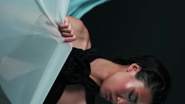 Parlak makyajlı genç Asyalı modelin stüdyo dikey portresi. Etrafında rüzgarda uçuşan ipek parçaları. - Video, Çekim