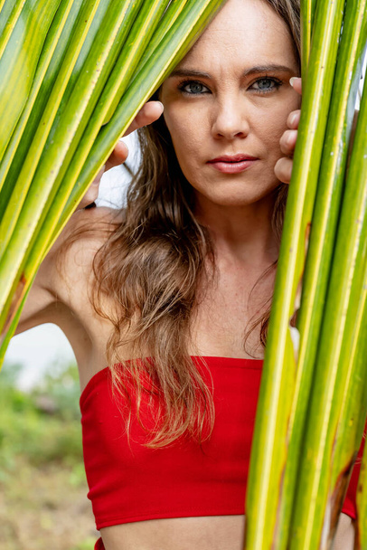 Oszałamiająca brunetka, promieniująca w tętniącej życiem czerwonej sukience, z elegancją urzeka wybrzeże Karaibów, ucieleśniając piękno pośród tropikalnego raju - Zdjęcie, obraz