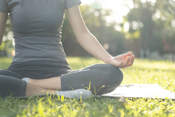 Een vrouw die mediteert in het park. Aziatische vrouw doet 's morgens oefeningen. balans, recreatie, ontspanning, kalm, goede gezondheid, gelukkig, ontspannen, gezonde levensstijl, stress verminderen, vreedzaam, Attitude. - Foto, afbeelding