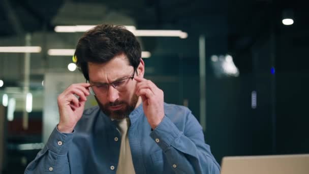 Gestresste man in casual kleding die bril afdoet en hoofd op hoofd rust tijdens het werk. Overbelaste mannelijke econoom die breekt met het tellen van rekeningen voor de stabilisatie van het zenuwstelsel. - Video