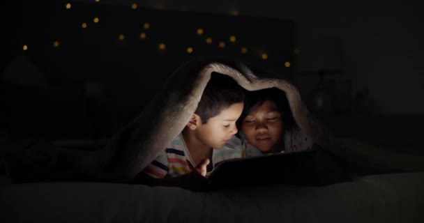 Tablet, gece ve yatağında çizgi film, oyun ya da film olan çocuklar battaniye kalesindeki film videosu. Aile, kardeşler ya da yatak odasındaki çocuklarda sevgi, bağ ya da dijital, arama ya da hikaye anlatma uygulaması. - Video, Çekim