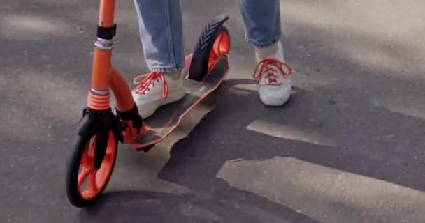 Fille sportive chevauche scooter moderne sur asphalte route gros plan. Adolescente aime passer du temps actif sur une journée ensoleillée le week-end. Sports extrêmes - Séquence, vidéo