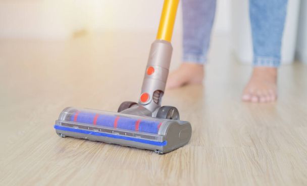 Frau putzt den Holzboden im Wohnzimmer mit Staubsauger. Hausputzkonzept, selektiver Fokus. - Foto, Bild