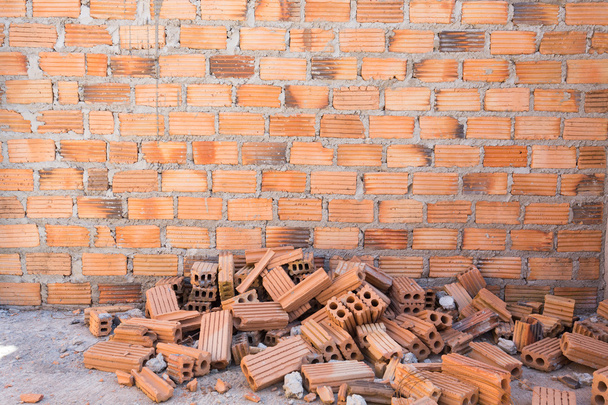 Куча кирпичей на строительной площадке на фоне кирпичной стены
 - Фото, изображение
