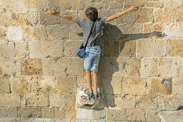 Το αγόρι κάνει ευχές σε μια μαγική πέτρα με γυρισμένη την πλάτη. ταξίδι σε ευρώ - Φωτογραφία, εικόνα