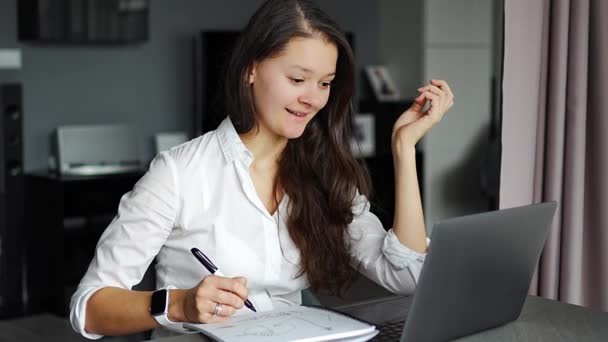 Mujer joven que utiliza el ordenador portátil en el lugar de trabajo en casa, notas de escritura, concepto de educación e-learning. Imágenes de alta calidad 4k - Imágenes, Vídeo