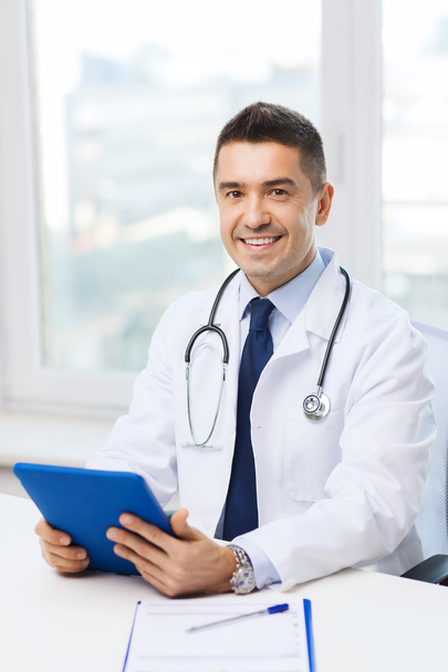 smiling male doctor in white coat with tablet pc - Фото, изображение