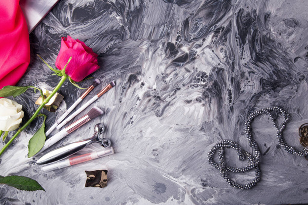 Glamorous makeup tools and fresh flowers set against a monochrome fluid art background. - Photo, Image