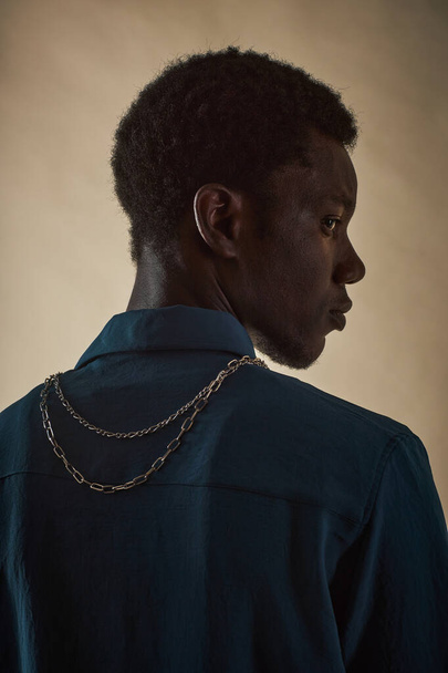 首に金属の鎖が付いているカメラから直面する若い黒人男性のプロフィールビューの肖像画,ファッションの付属品の概念 - 写真・画像