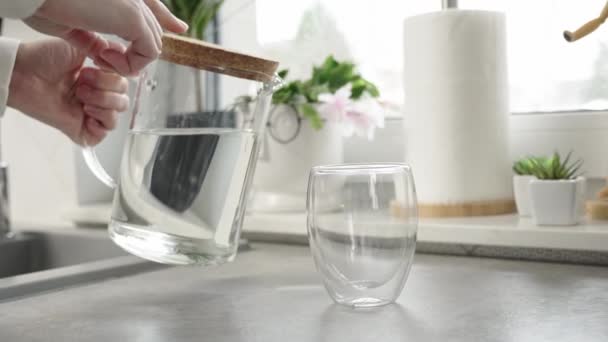 Vrouw gieten vers zuiver water uit kan in glas in de keuken, lessen dorst, Lifestyle gezondheidszorg concept - Video