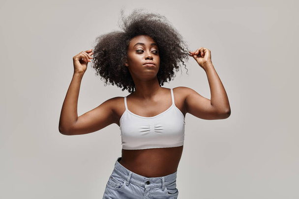 Une belle jeune afro-américaine aux cheveux bouclés pose dans un studio. - Photo, image