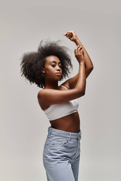 Uma jovem afro-americana com um penteado encaracolado faz uma pose confiante para uma foto. - Foto, Imagem