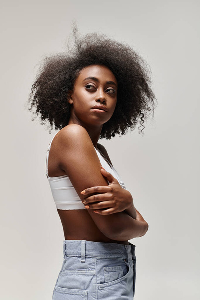 Luotettava Afrikkalainen Amerikkalainen nainen kihara afro hiukset seisoo kädet ristissä, tihkuu voimaa ja vaikutusmahdollisuuksia. - Valokuva, kuva