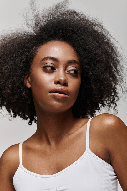 Μια όμορφη Αφροαμερικανή με σγουρά μαλλιά ποζάρει σε στούντιο.. - Φωτογραφία, εικόνα