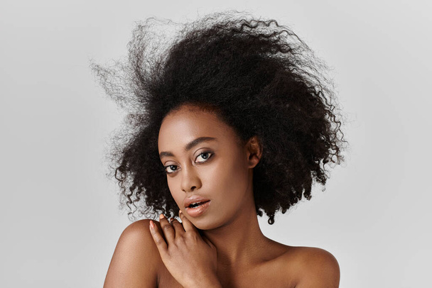 Μια νεαρή Αφρο-Αμερικανίδα με σγουρά μαλλιά ποζάροντας για ένα πορτραίτο, που δείχνει τα πολυτελή μαλλιά της. - Φωτογραφία, εικόνα
