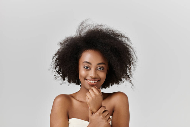 Μια όμορφη νεαρή Αφρο-Αμερικανίδα με σγουρά μαλλιά ποζάρει με αυτοπεποίθηση σε ένα στούντιο για μια φωτογραφία. - Φωτογραφία, εικόνα