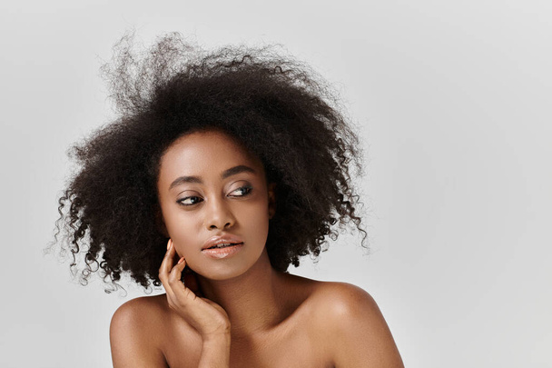 Une superbe Afro-Américaine aux cheveux bouclés frappant une pose en studio. - Photo, image