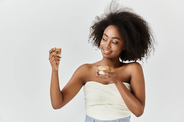 Egy fiatal afro-amerikai nő, göndör hajjal, tejszínnel a kezében. - Fotó, kép
