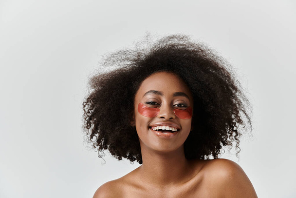 Una hermosa joven afroamericana con el pelo rizado mostrando bajo parches en los ojos - Foto, imagen