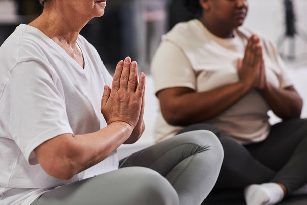 Крупним планом жінки, які сидять на позиції лотоса і медитують під час занять з йоги - Фото, зображення