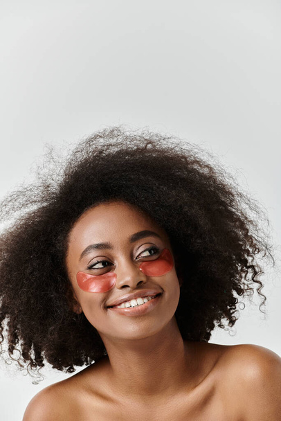 Stüdyoda kıvırcık saçlı, göz bandı takan güzel bir Afrikalı Amerikalı kadın.. - Fotoğraf, Görsel