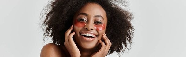 Kaunis nuori afroamerikkalainen nainen, jolla on kiharat hiukset, esittelee ihonhoitokonseptin - Valokuva, kuva