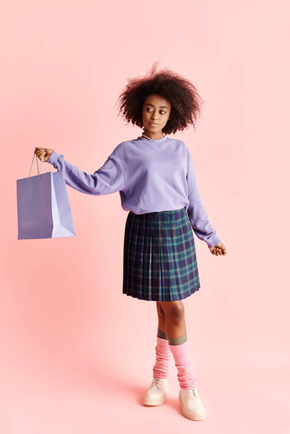 Una mujer afroamericana con estilo en una falda sostiene una bolsa de compras, exudando moda y elegancia en un entorno de estudio. - Foto, Imagen
