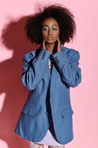 Stüdyoda fotoğraf çekimi için mavi ceketle poz veren kıvırcık saçlı şık Afrikalı genç bir Amerikalı kadın.. - Fotoğraf, Görsel