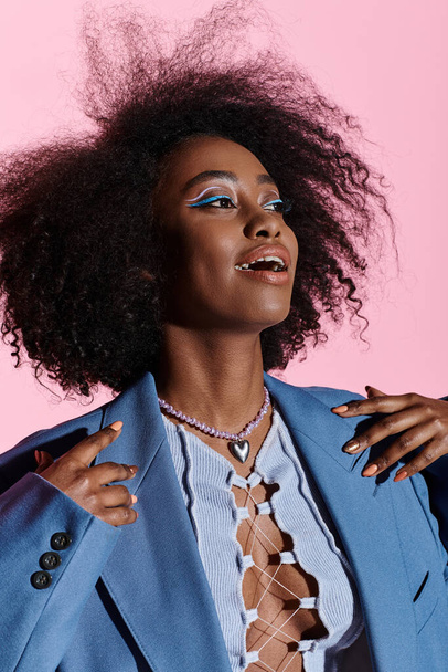 Stylish young African American woman with curly hair wearing a blue suit poses confidently in a studio setting. - Photo, Image