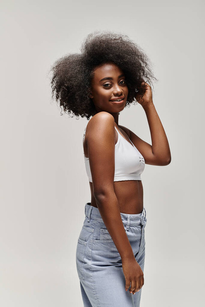 Μια νεαρή Αφρο-Αμερικανίδα με σγουρά αφρο μαλλιά που ποζάρει για μια φωτογραφία σε ένα στούντιο.. - Φωτογραφία, εικόνα
