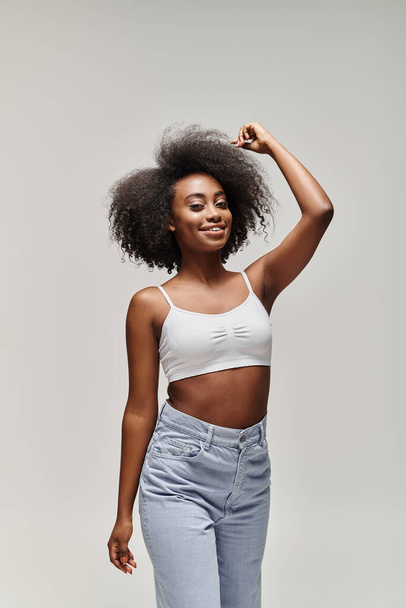 Una joven afroamericana impresionante con el pelo rizado, estilizado en un afro, posa con confianza para una cámara. - Foto, imagen