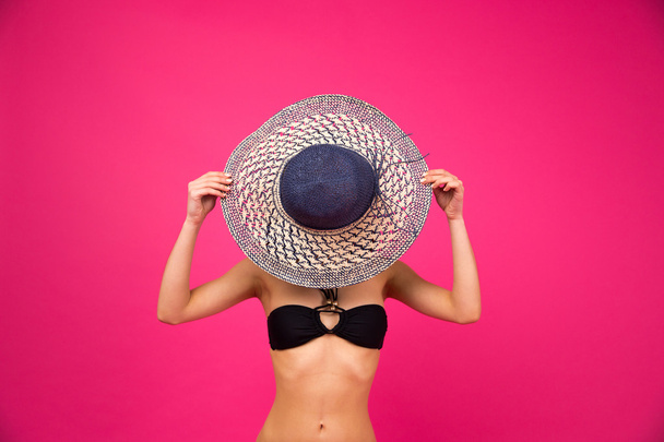 Woman in bikini covering her face with hat - Foto, afbeelding