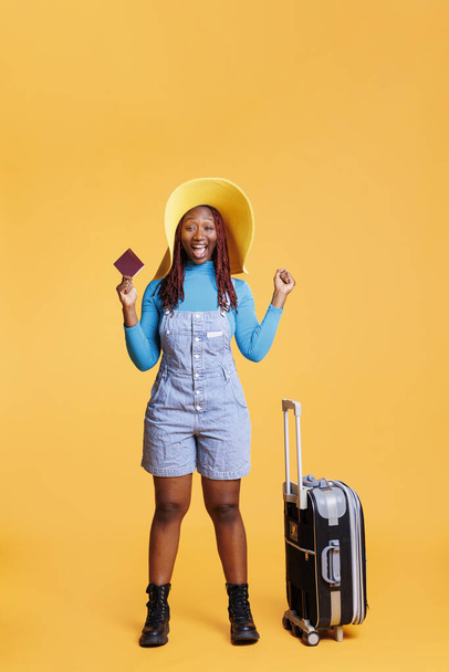 Smiling person being excited about trip, using passport to travel on international holiday destination. Female adult leaving on urban adventure with trolley bags, weekend activities. - Photo, Image