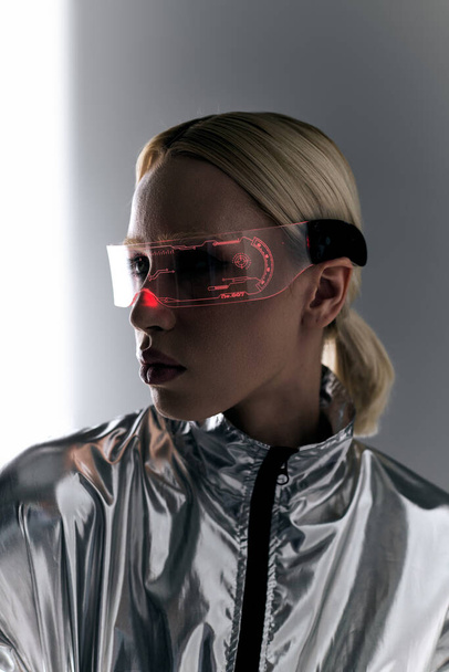 appealing woman with futuristic glasses in robotic silver attire looking away on gray backdrop - Фото, зображення