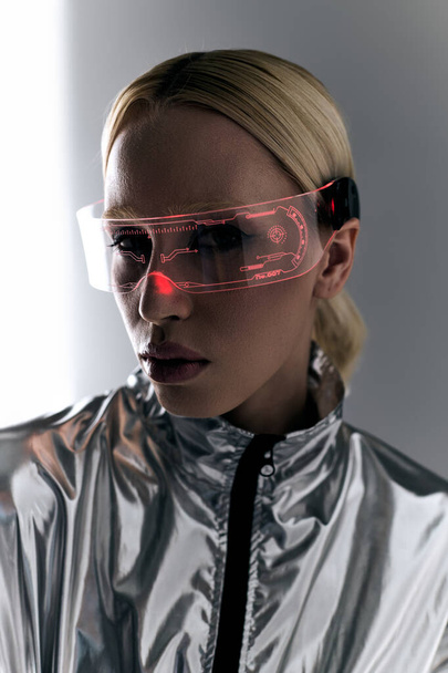 extraordinary woman with sci fi glasses in robotic silver clothing looking at camera on backdrop - Photo, Image