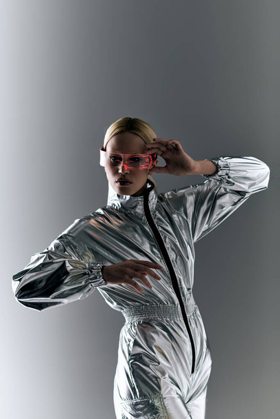 peculiar woman with sci fi glasses in futuristic attire doing robotic motions and looking at camera - Foto, imagen